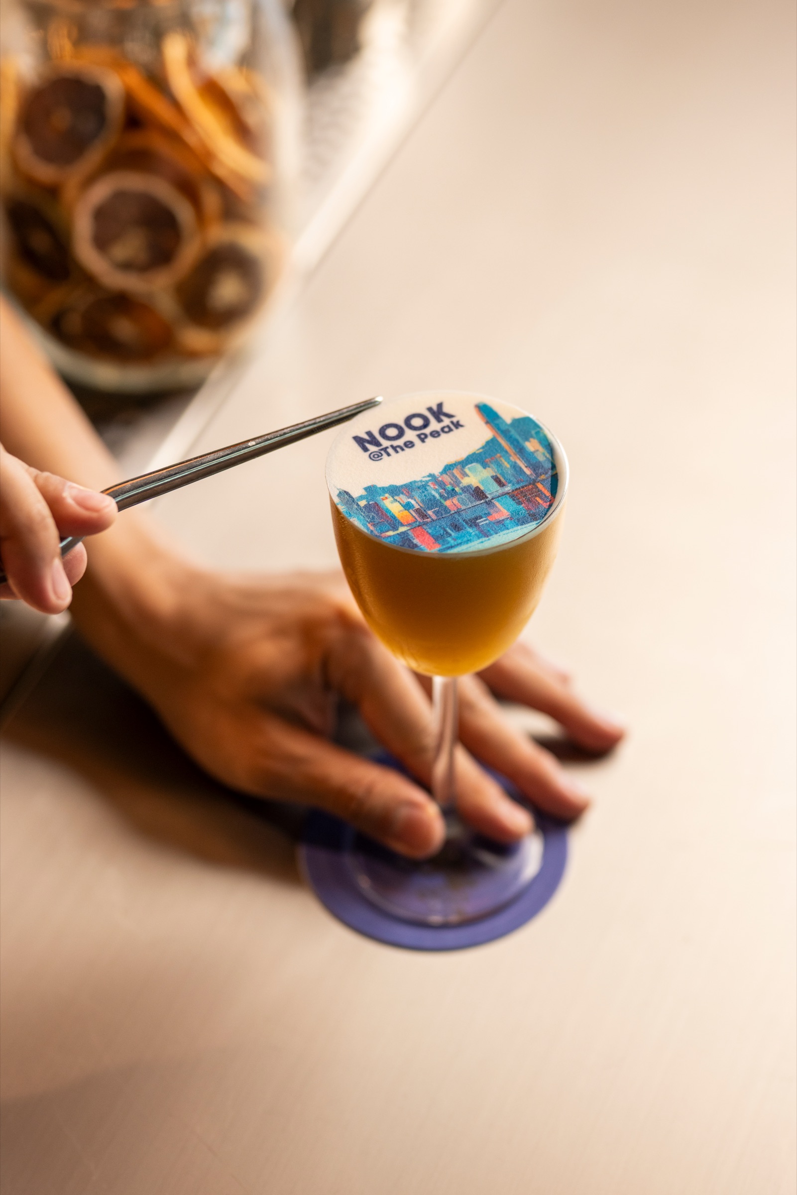 Cocktail with a printed NOOK@The Peak skyline at the bar