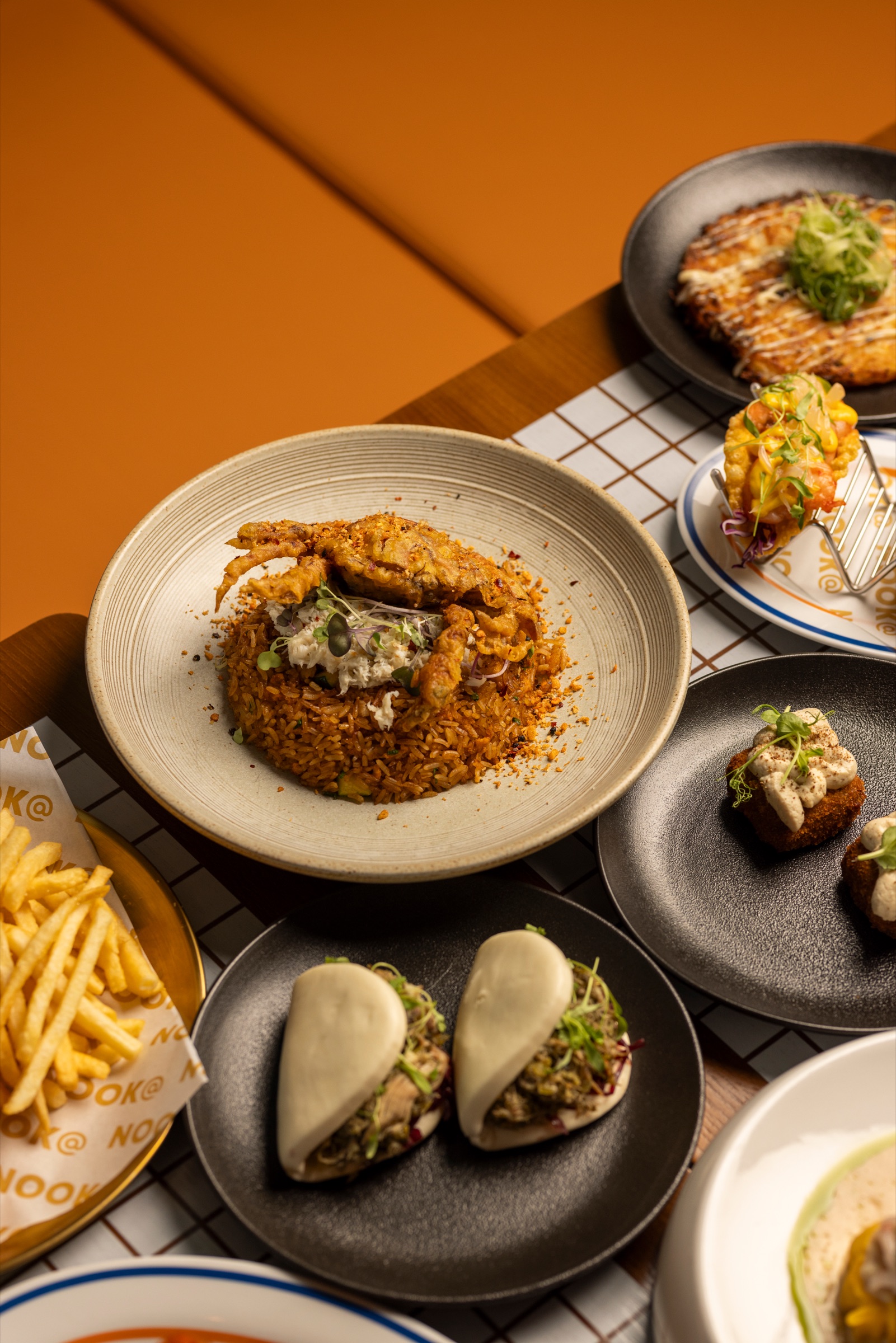 A shared table of dishes at NOOK@The Peak